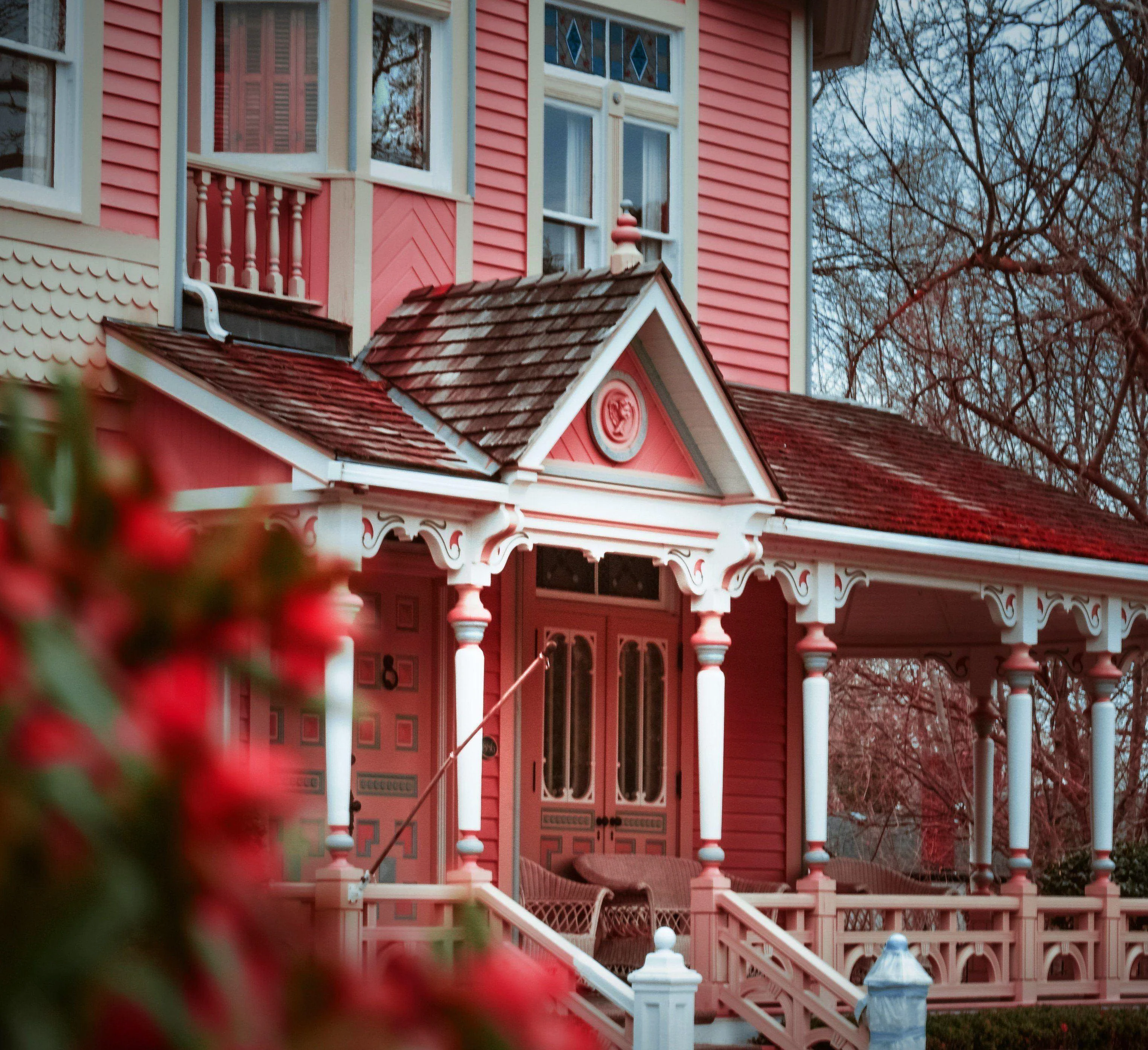 A zoomed in image of the outside of a pink Victorian house